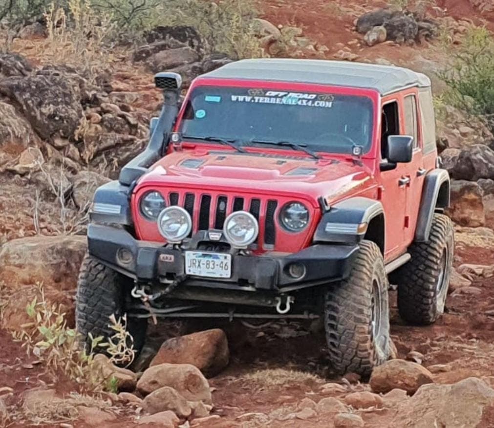 Jeep Wrangler roja de frente sobre terracería entre rocas